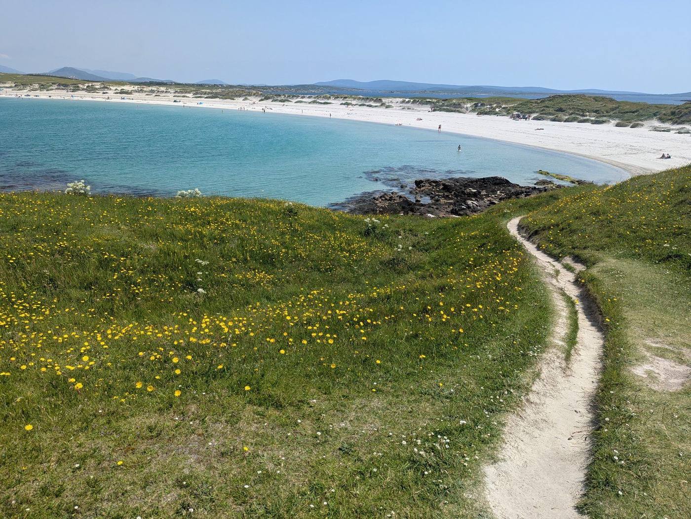 The grassy path with wildflowers leading from Gurteen Bay over to Dog's Bay