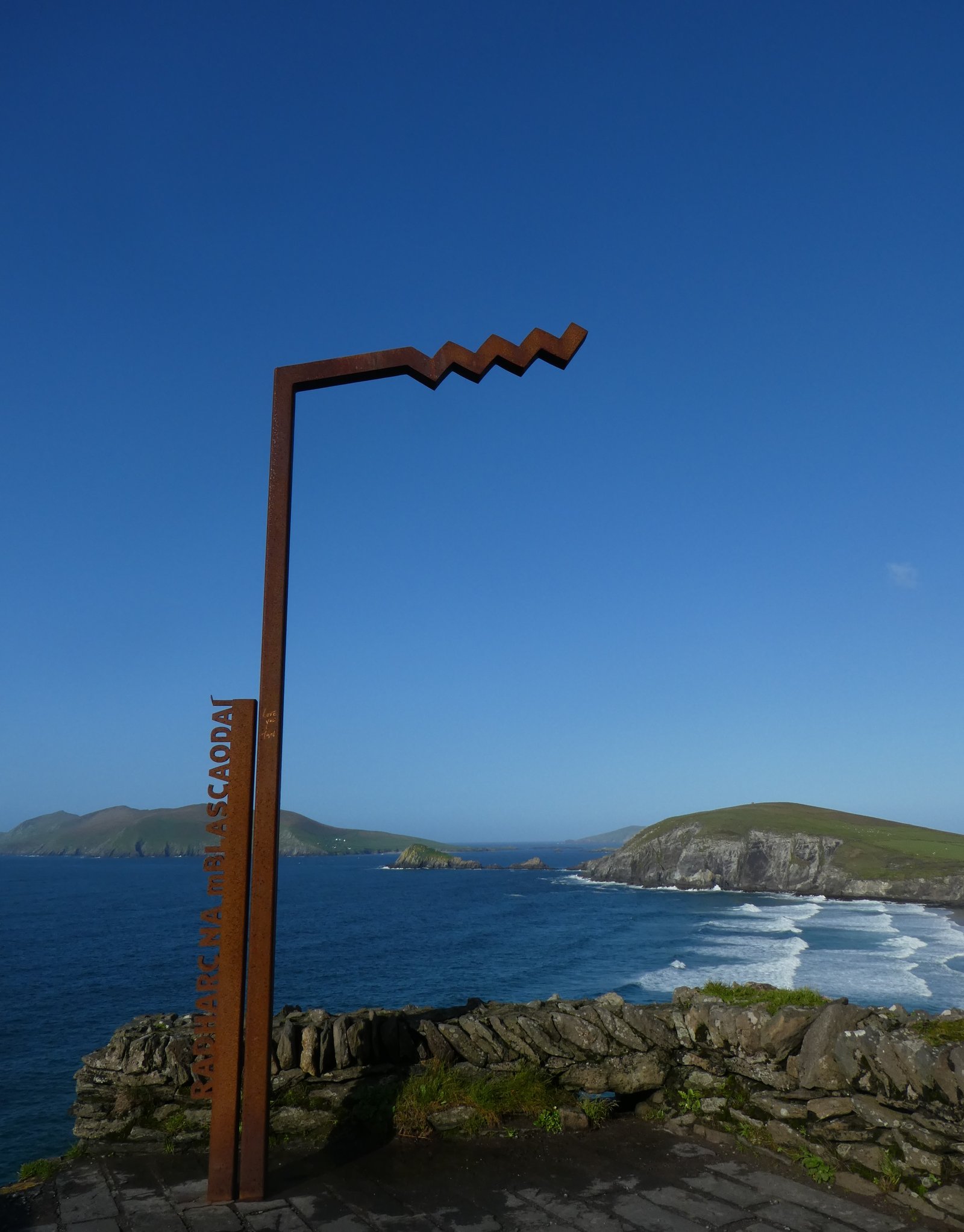 The rust-coloured Corten steel sculpture marking the Radharc na mBlascaoidí viewpoint, framing the Blasket Islands and the Atlantic beyond
